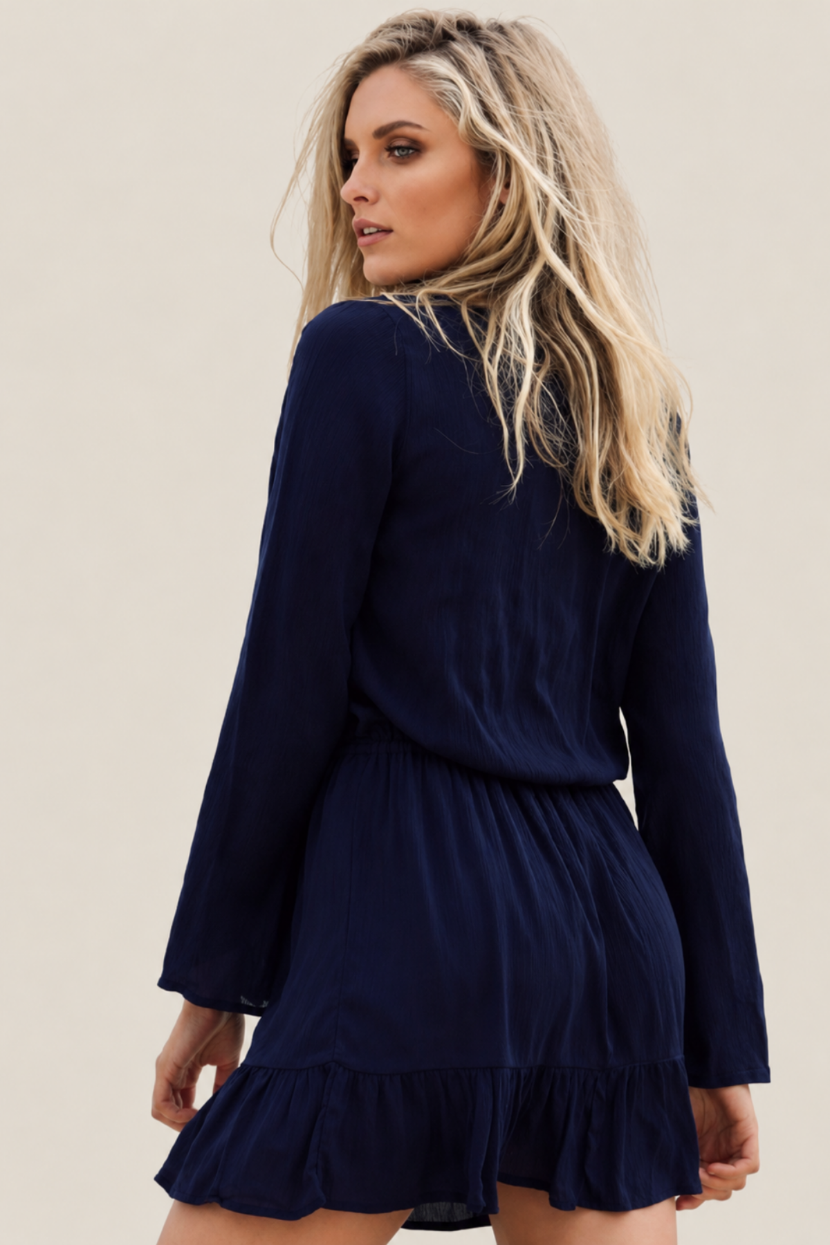 Modelo de espaldas con vestido corto Wilde Heart de manga larga en color navy, mostrando el diseño ajustado y elegante del respaldo sin costuras visibles