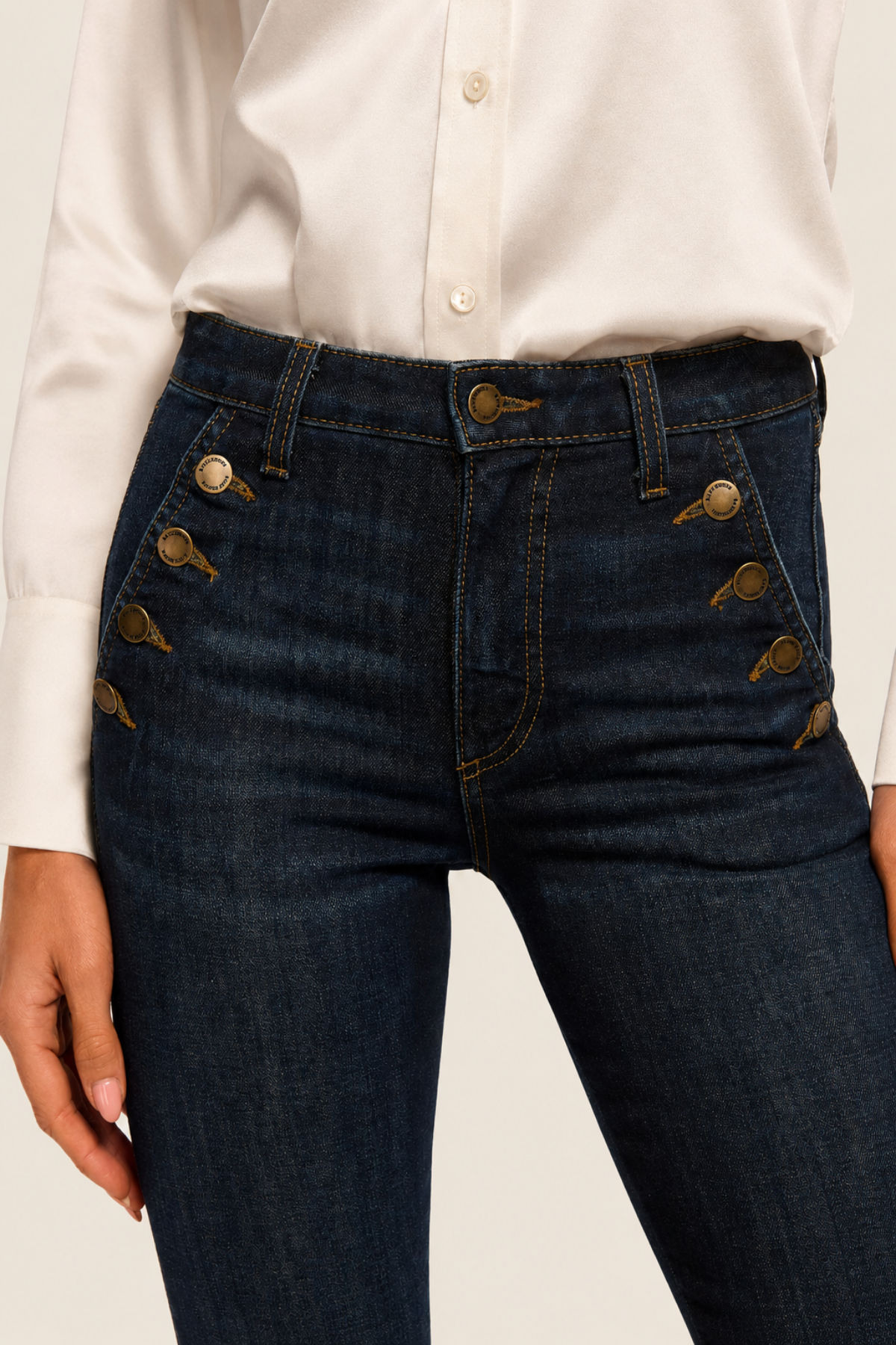 Detalle de la botonera frontal del pantalón flare dark rinse, con botones marineros y cierre de cremallera discreto