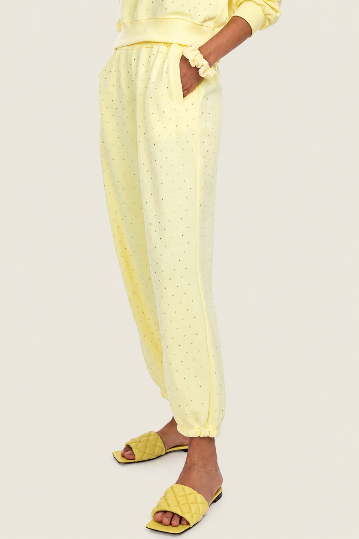 Primer plano de la modelo con Rena Crystal yellow sweatpants con las manos en los bolsillos, reflejando estilo relajado y funcionalidad
