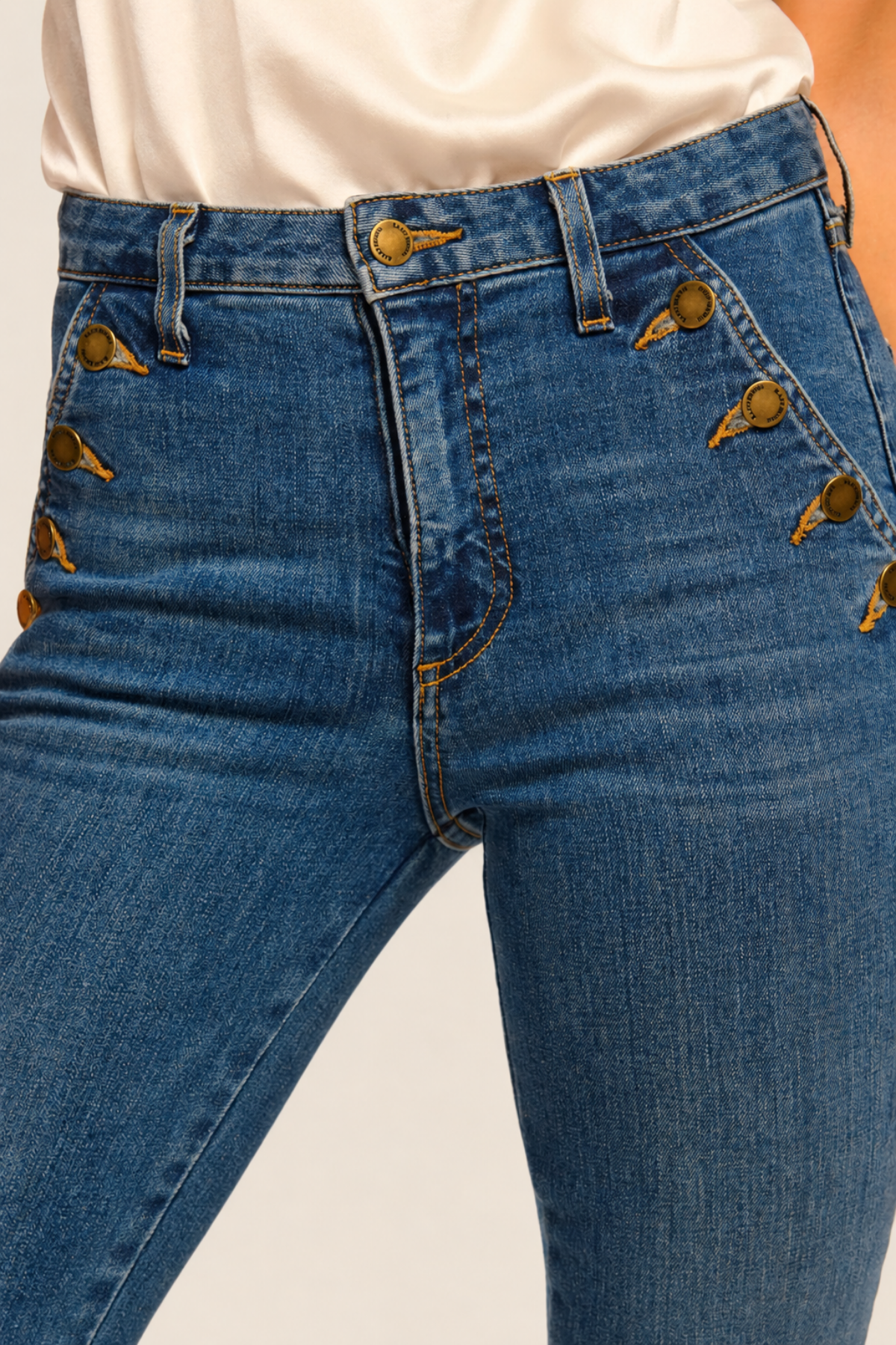Detalle frontal de la botonera del pantalón flare Medium Wash con botones visibles y cierre de cremallera discreto para estilismo moderno