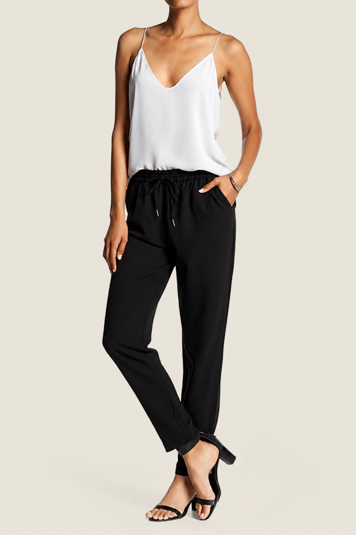 Modelo posando sobre fondo blanco con los pantalones Joie Janeene en negro, destacando el cordón ajustable, corte tobillero y estilo moderno y elegante