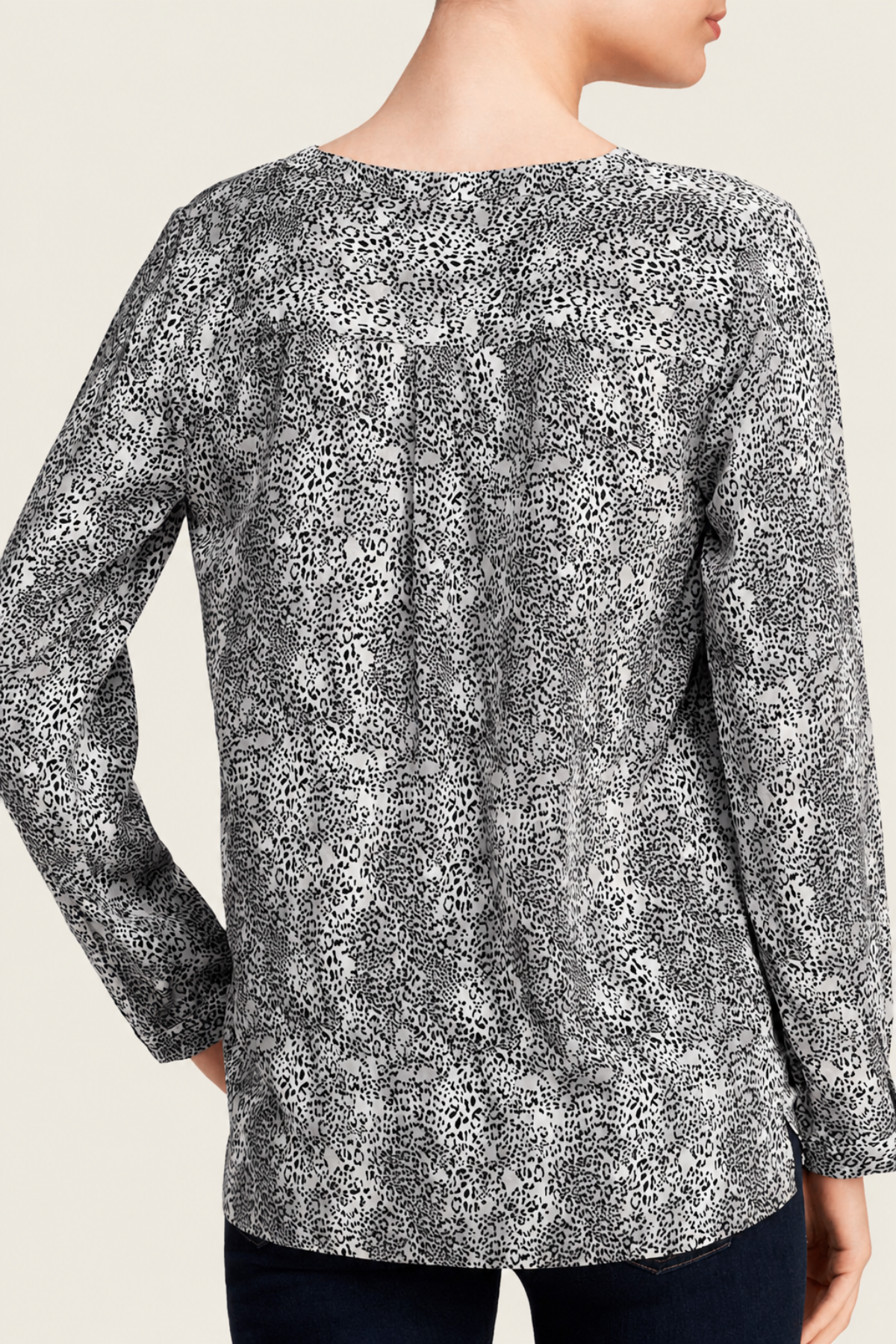 Detalle del estampado cheetah en negro sobre la seda blanca de la blusa Joie Michi, realzando textura y diseño sofisticado
