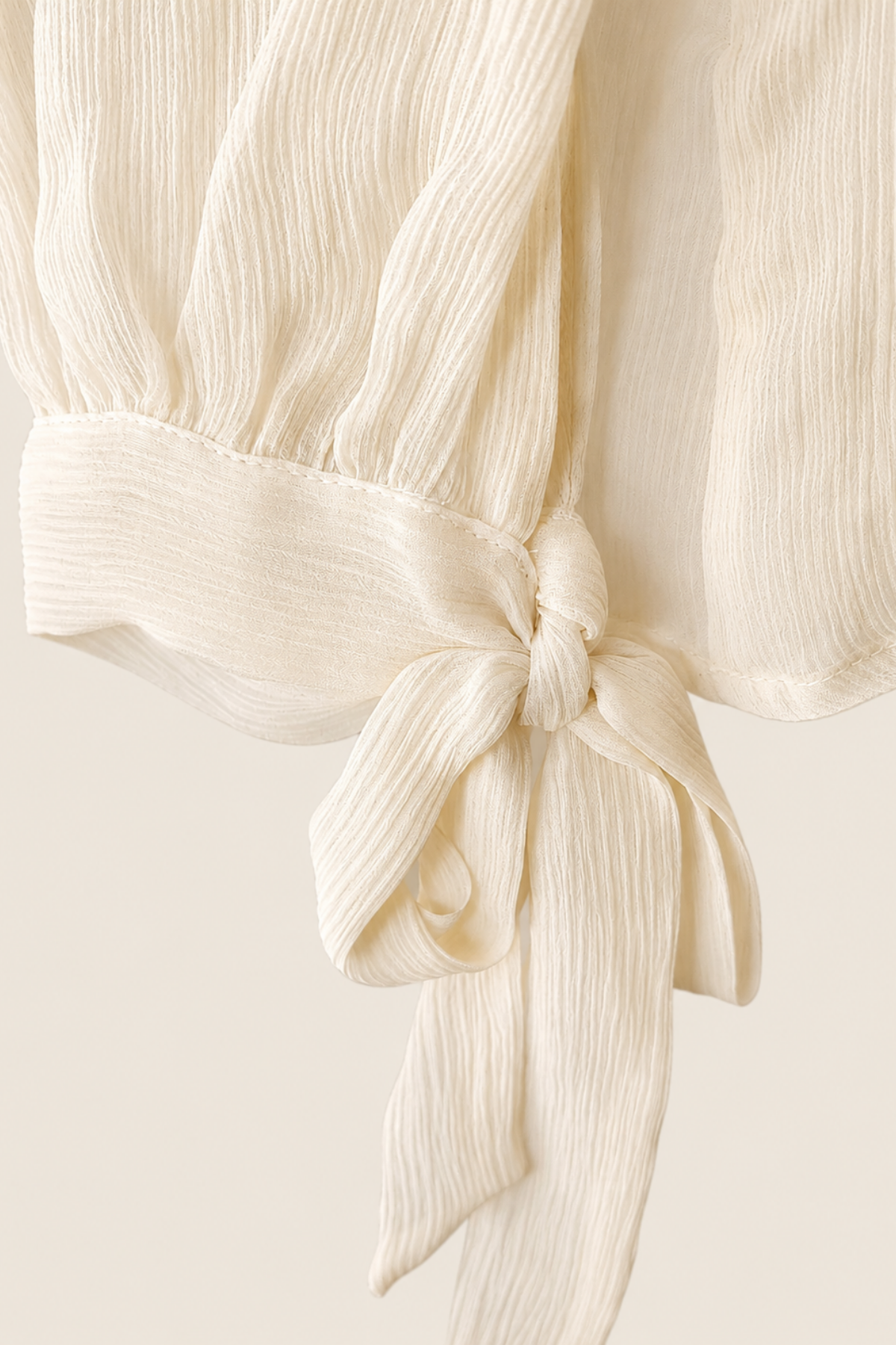 Detalle lazo delantero blusa Luisa Becaria marfil de seda plisada mostrando textura suave y acabado artesanal italiano