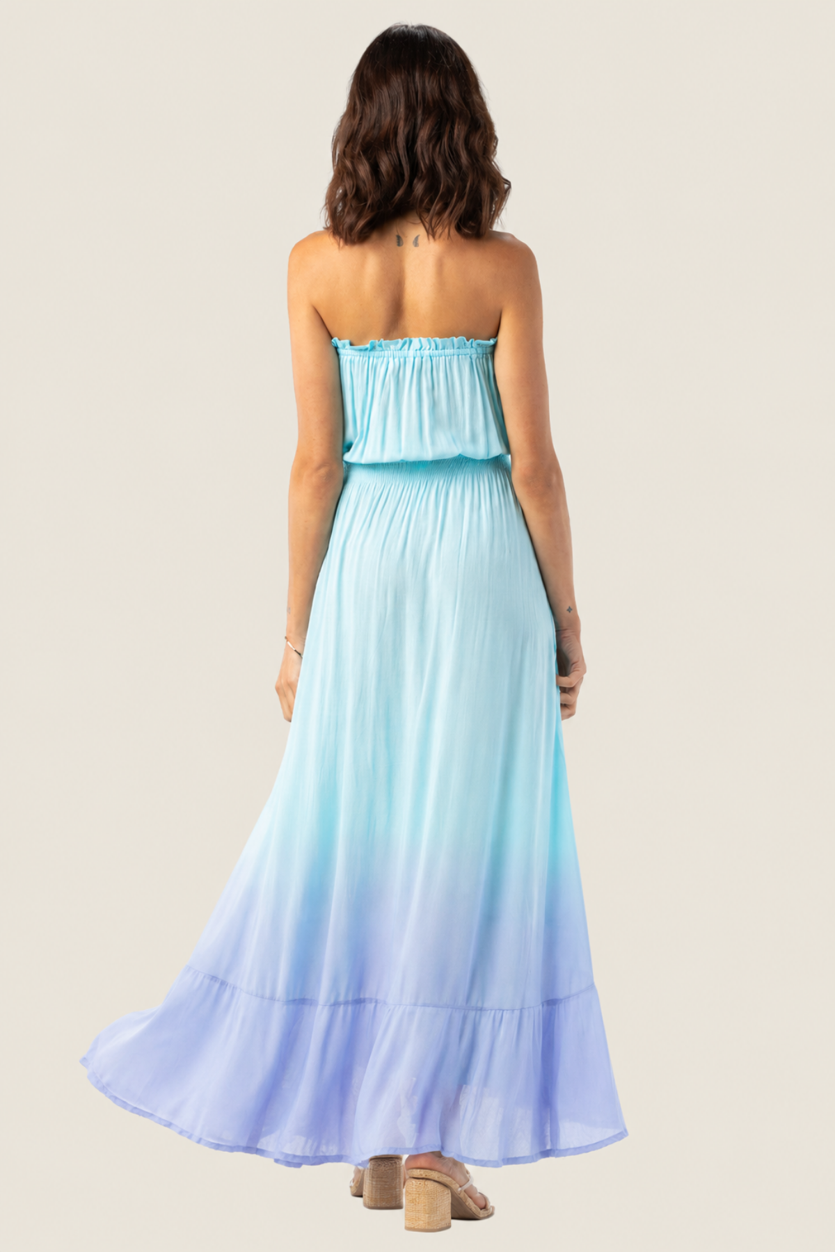 Modelo posando de espaldas con vestido largo Ryden de Tiare Hawaii mostrando el diseño y corte trasero del vestido