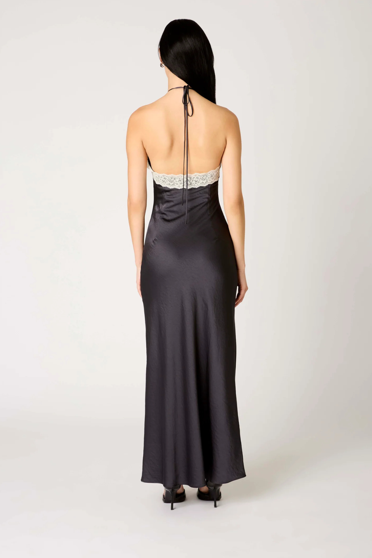 Vista trasera del vestido largo Vesper en color soot black, mostrando la caída fluida del tejido y la silueta elegante de la espalda
